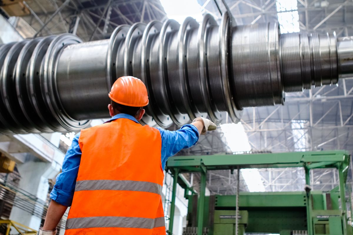 Techniker mit Helm und Warnweste an einem großen Turbinenrotor